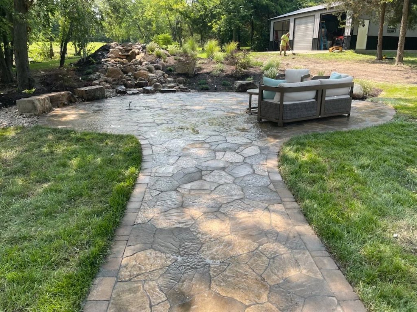 A stamped stone patio with outdoor seating and a curved walkway
