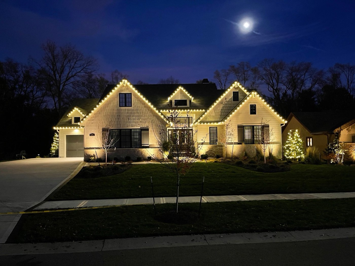 Two-story home outlined in warm white Christmas lights at night