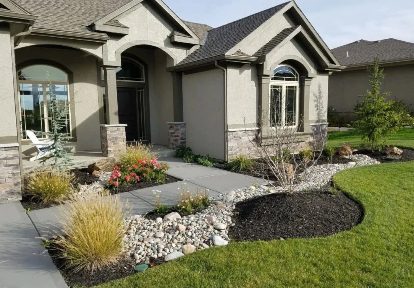 Front yard beds with river rock, grasses and black mulch