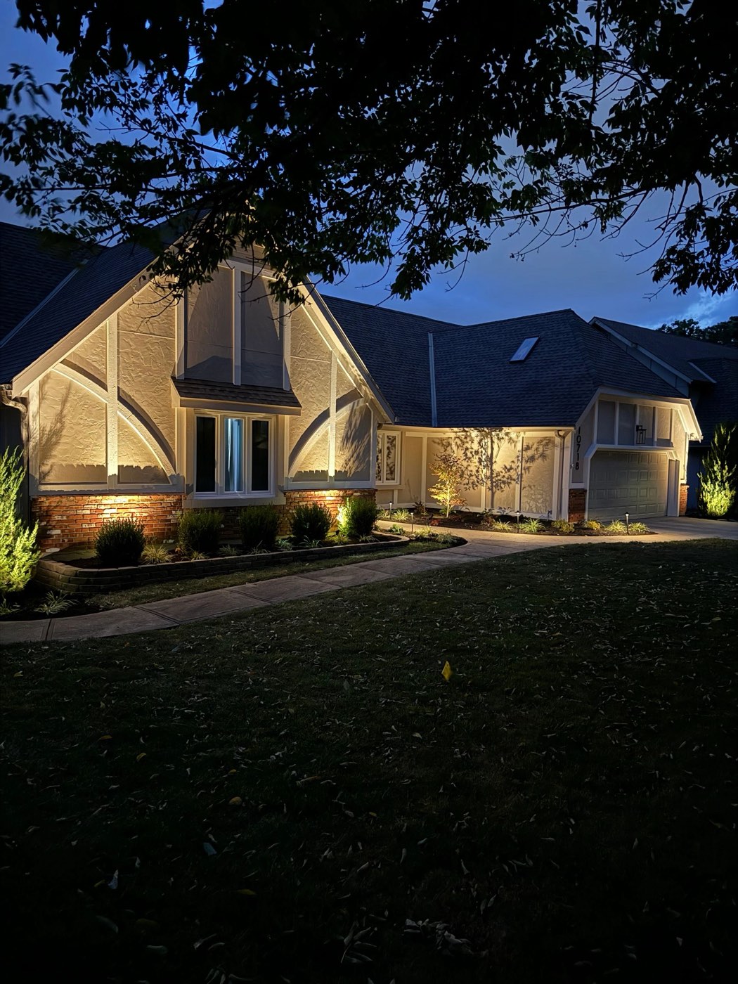 Home and front yard with landscape lighting at night