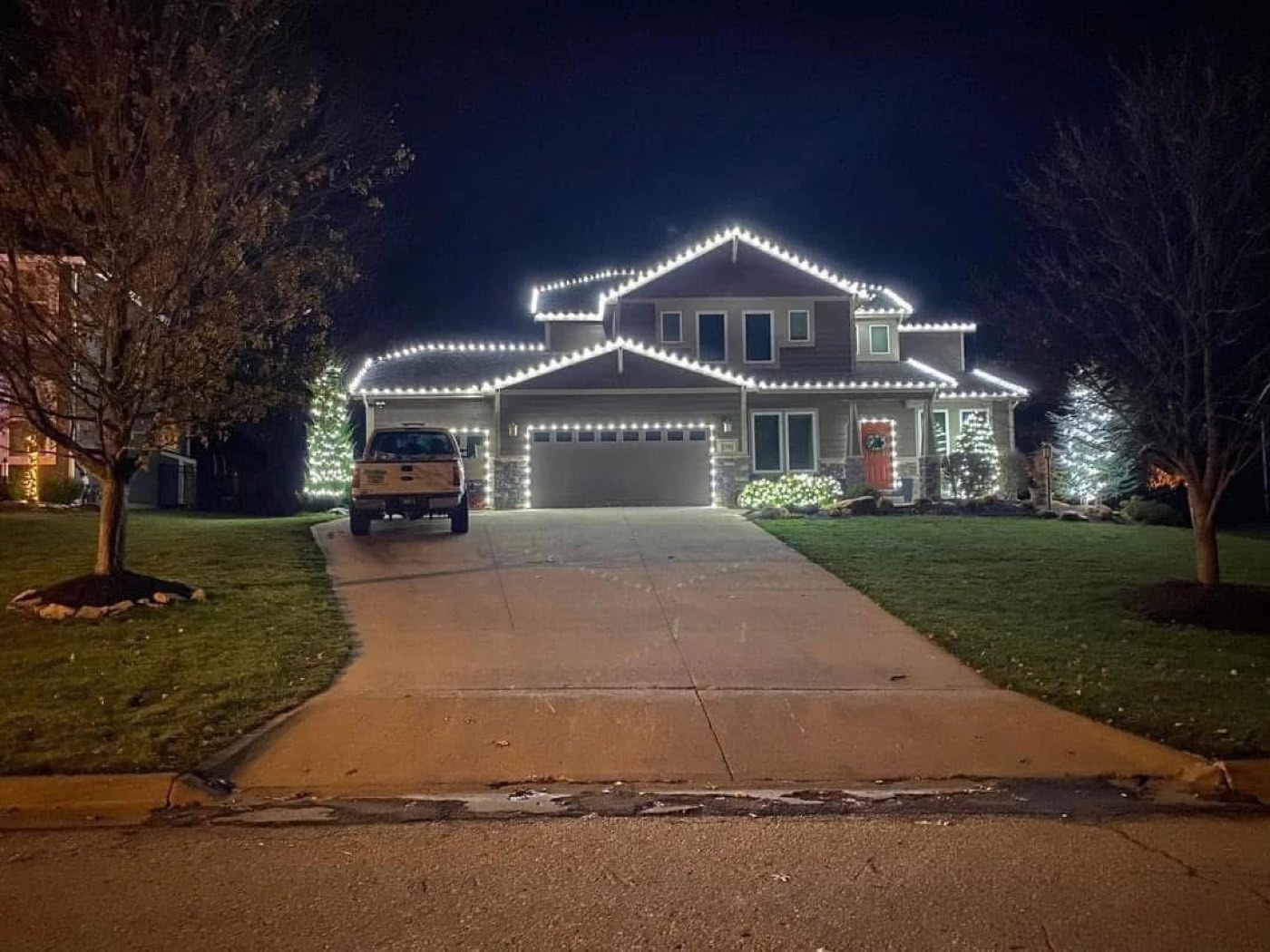 Two-story home and driveway trees in holiday lights