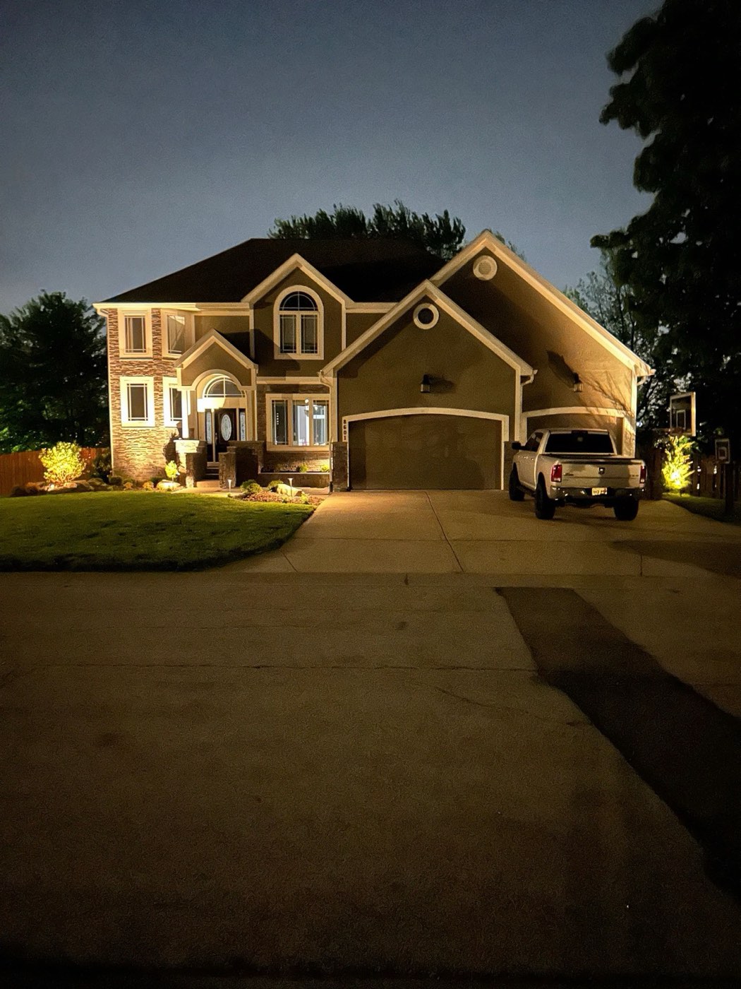 Two-story home with landscape lighting at night