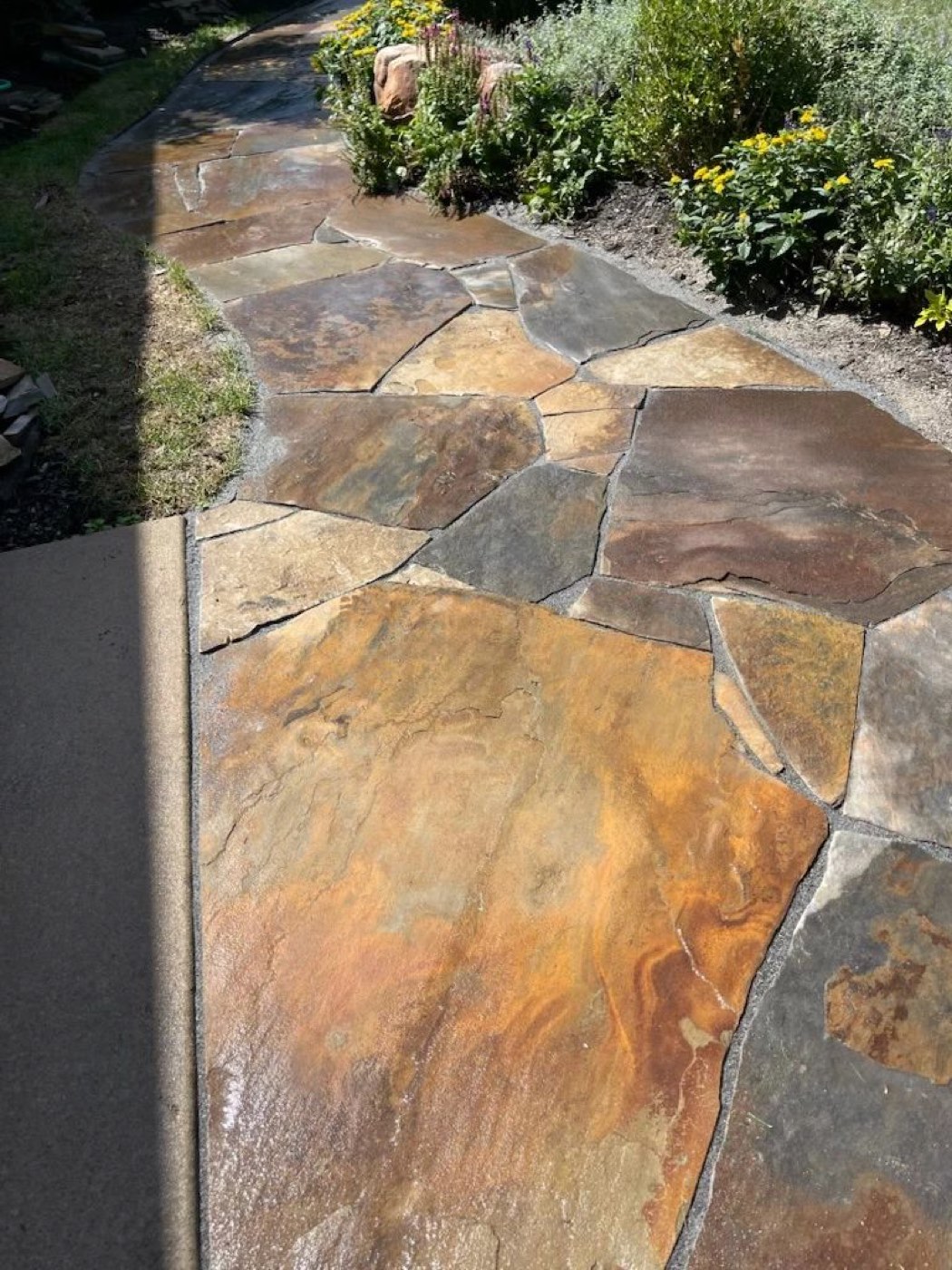 Natural flagstone walkway beside a planted bed