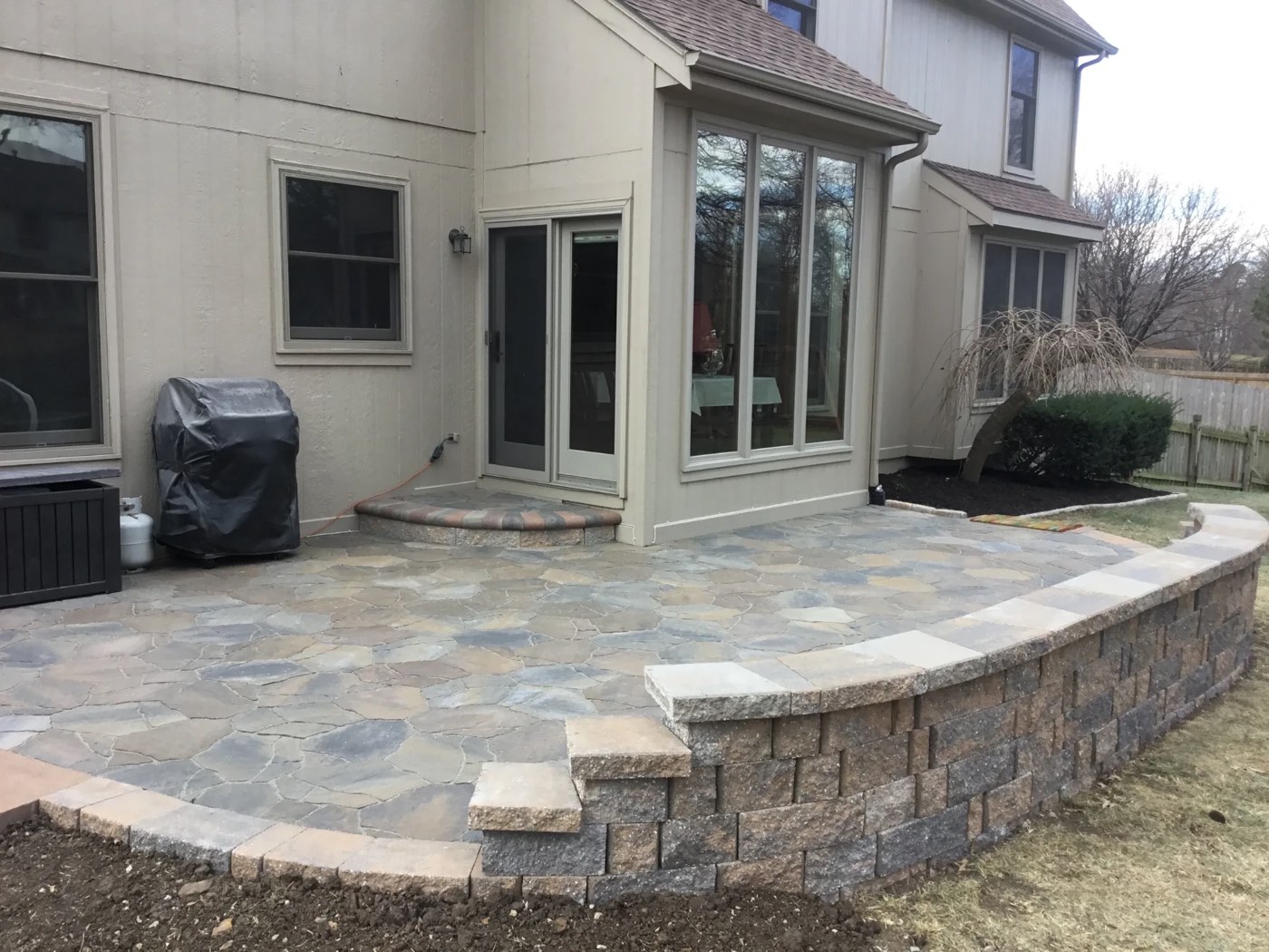 Flagstone-pattern paver patio with a curved seat wall and step